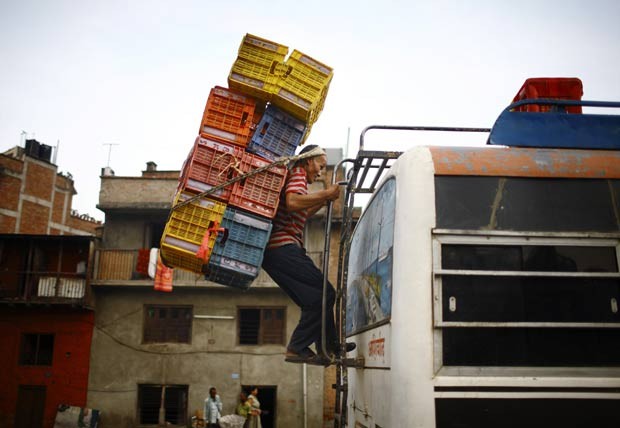 Sustentando o peso com a cabeça, homem carregou diversas caixas nas costas. (Foto: Navesh Chitrakar/Reuters)