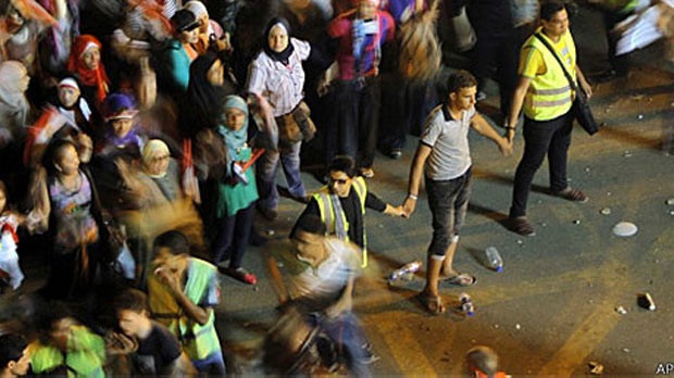 Voluntários usando coletes amarelos protegem mulheres na praça Tahrir (Foto: AP)