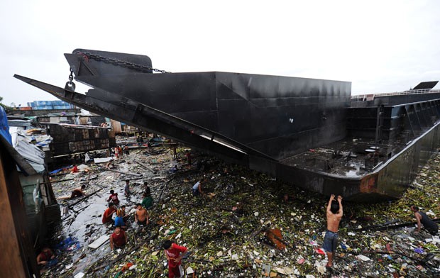 Barco invadiu comunidade inundada com aproximação de tempestade tropical em Manila, nas Filipinas (Foto: Ted Aljibe / AFP)