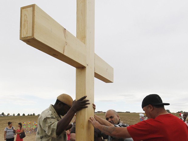 Homem reza sobre cruz levada a memorial para as vítimas do massacre de Aurora (Foto: REUTERS/Rick Wilking)