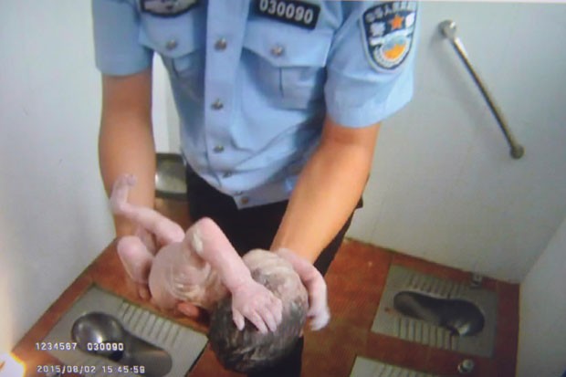 Policial segura beb recm-nascido abandonado em banheiro pblico de Pequim, na China, nesta segunda-feira (3) (Foto: AFP)