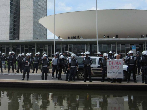 Junto a barreira de policiais, manifestante pró-Dilma exibe cartaz em frente ao Congresso Nacional  (Foto: Vianey Bentes/TV Globo)