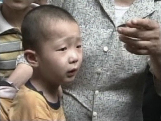 Menino é visto com seus familiares após ser resgatado de uma fenda entre paredes na China (Foto: CCTV/Reuters)
