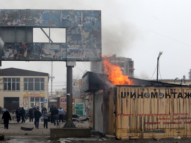 Moradores observam incêndio na cidade portuária de Mariupol, na Ucrânia, depois de bombardeio promovido por rebeldes (Foto: Stringer/AFP)