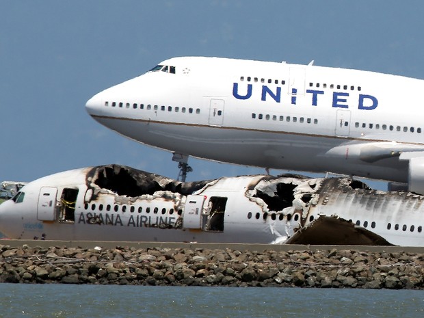 Avião decola ao lado de destroços do boeing 777 da Asiana Airlines no Aeroporto Internacional de San Francisco, dois dias depois do acidente que deixou dois mortos. (Foto:  Justin Sullivan/Getty Images/AFP)