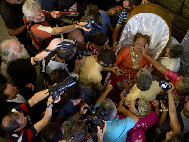 Cercada pela imprensa após o fim da Procissão das Mortalhas, mulher chora ao conceder entrevista ainda dentro de um caixão na igreja de Santa Marta, em Santa Marta de Ribarteme, na Espanha, na quarta (29) (Foto: AFP Photo/Miguel Riopa) Cercada pela imprensa após o fim da Procissão das Mortalhas, mulher chora ao conceder entrevista ainda dentro de um caixão na igreja de Santa Marta, em Santa Marta de Ribarteme, na Espanha, na quarta (29) (Foto: AFP Photo/Miguel Riopa)