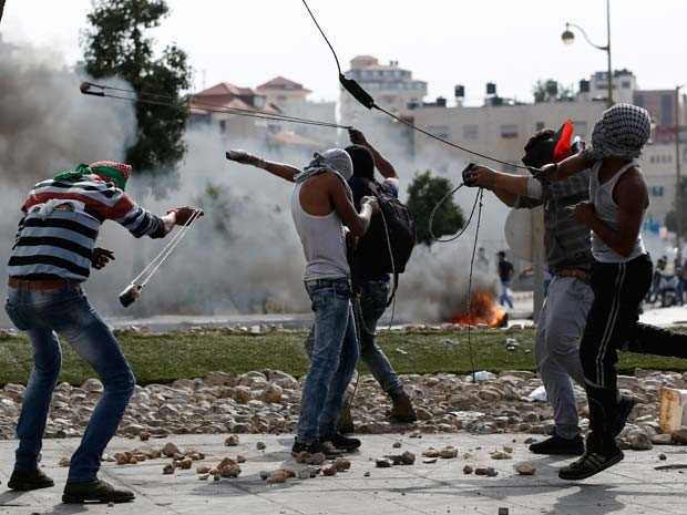 Manifestantes palestinos jogam pedras contra soldados de Israel durante confronto nesta terça-feira (20) na cidade de Al-Bireh, na Cisjordânia (Foto: AFP PHOTO / ABBAS MOMANI)