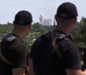 Policiais da República Popular de Donetsk observam bombardeio contra a cidade de Shakhtarsk. Após a queda do avião da Malaysia Airlines, o Exército de Kiev intensificou a ação militar no leste da Ucrânia (Foto: AP Photo/Dmitry Lovetsky)