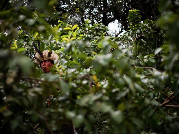 Indígena encara a polícia dentre a vegetação do terreno do antigo Museu do Índio, conhecido como Aldeia Maracanã, no Rio. O prazo para desocupação do local acaba na quarta (20), mas um dos líderes dos indígenas disse ao G1 que o grupo não pretende sair. (Foto: Christophe Simon/AFP)