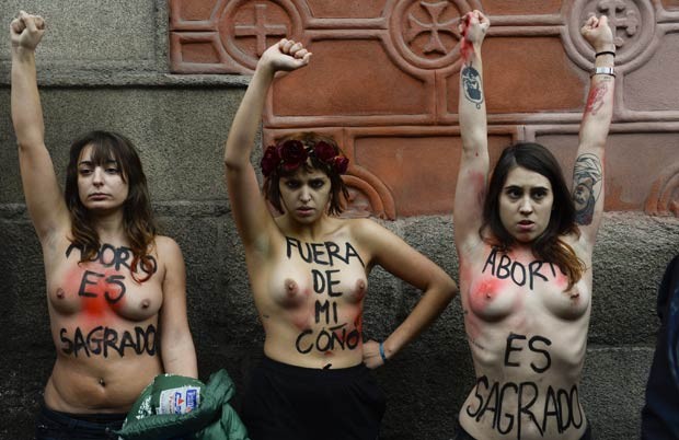 Ativistas erguem os braços, com frases de protesto escritas em seus corpos, em Madri (Foto: Pierre-Philippe Marcou/AFP)