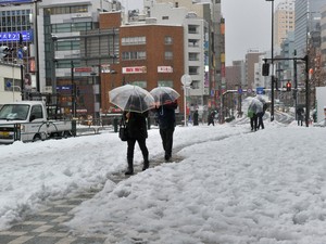 Pedestres caminham em rua coberta de neve em Tóquio, neste sábado (15)  (Foto: AFP)