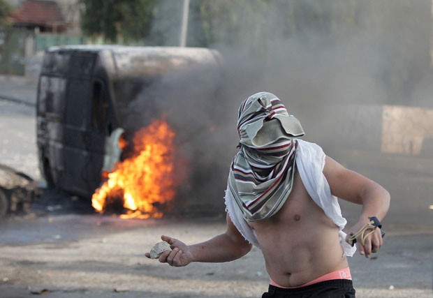 Em foto do dia 30 de outubro, palestino mascarado lança pedra contra forças de segurança israelenses em Jerusalém (Foto: Ahmad Gharabçi/AFP)