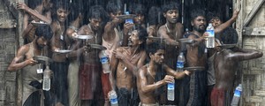 Imigrantes resgatados de barco coletam água da chuva em Myanmar (Soe Zeya Tun/Reuters)