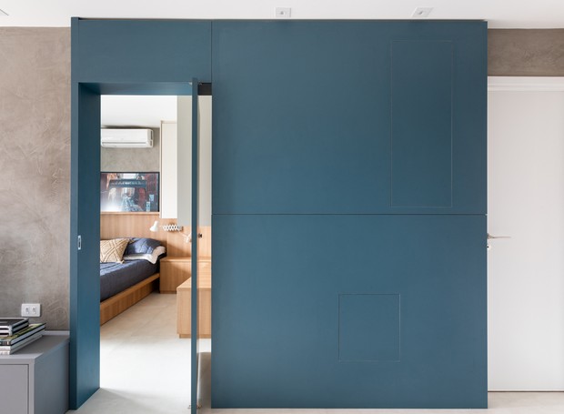 Painel azul de marcenaria camufla a porta pivotante que dá acesso ao quarto e esconde os quadros de energia e telefonia (Foto: Lufe Gomes/Divulgação)