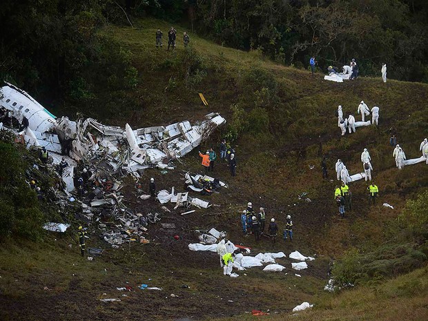 Equipes de resgate leva corpos embalados após retirá-los dentre os destroços do avião da LaMia perto de Medellín, na Colômbia (Foto: Raul Arboleda/AFP)