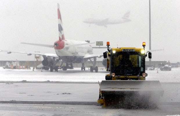 Um carro limpa a neve acumulada no aeroporto de Heathrow, em Londres, na sexta-feira (18) (Foto: Steve Parsons/AP)