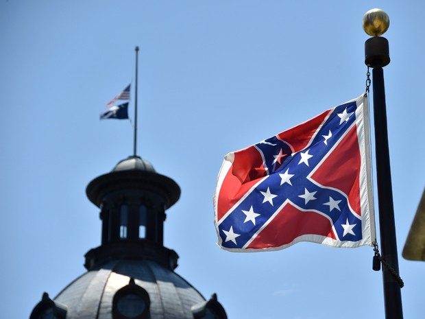 Em foto de 19 de junho, as bandeiras dos EUA e da Carolina do Sul so vistas a meio mastro, enquanto a bandeira confederada continua hasteada normalmente em frente ao prdio do governo estadual (Foto: AFP Photo/Mladen Antonov)