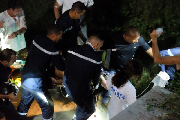  Paramédicos transportam mulher ferida em uma maca depois de ela ter sido atacada por um tubarão perto de praia da ilha francesa Reunião (Foto: AP Photo/STR)