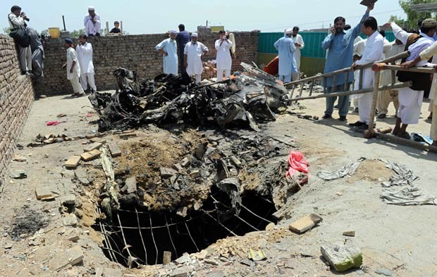 Moradores observam destroços de avião que caiu sobre casa em Rashkai, no Paquistão, nesta quinta-feira (17) (Foto: AFP)