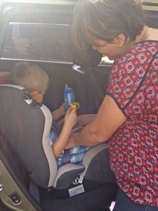 Flávia Buzato coloca o filho Lucas, de 3 anos, na cadeirinha, em Brasília (Foto: G1)