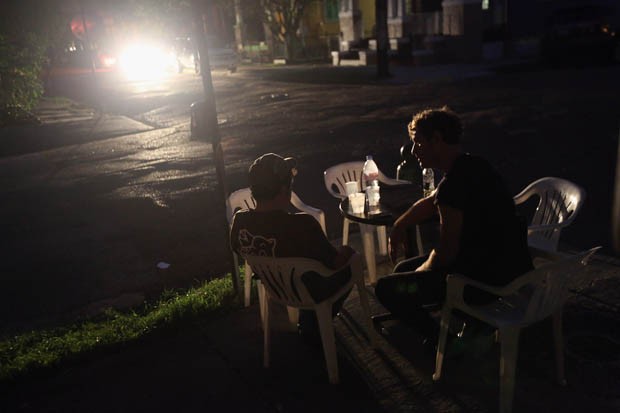 Homens conversam em uma mesa de bar iluminado por faróis de carro (Foto: John Moore/Getty Images/AFP)