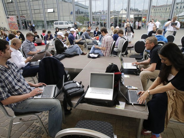 Pessoas usam seus notebooks ao ar livre durante o evento “Working Everywhere” (“trabalhando em todos os lugares”, na tradução livre) nesta sexta-feira (31), em Riga, capital da Letônia. (Foto: Ints Kalnins/Reuters)