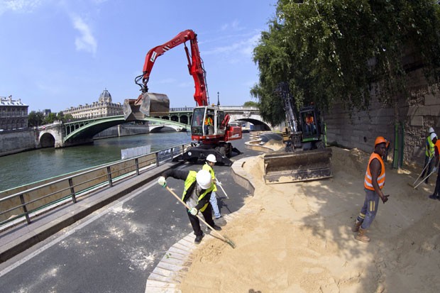Funcionários constroem praia artificial à beira do Rio Sena em Paris (Foto: Patrick Kovarik/AFP)