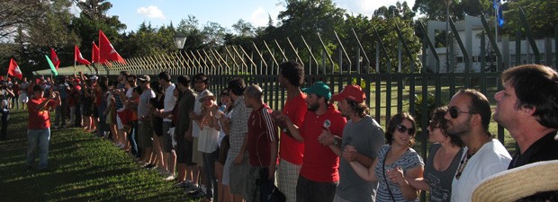 Manifestantes dão as mãos junto à grade da Embaixada do Paraguai, em Brasília (Foto: Fabio Amato / G1)