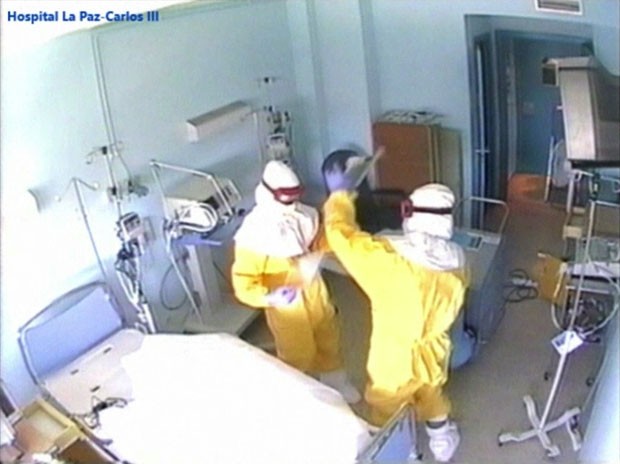 Imagem retirada de vídeo mostra funcionários em roupas especiais limpando o quarto onde o missionário Miguel Pajares foi tratado em Madri (Foto: Madrid Regional Health Authority/AP)