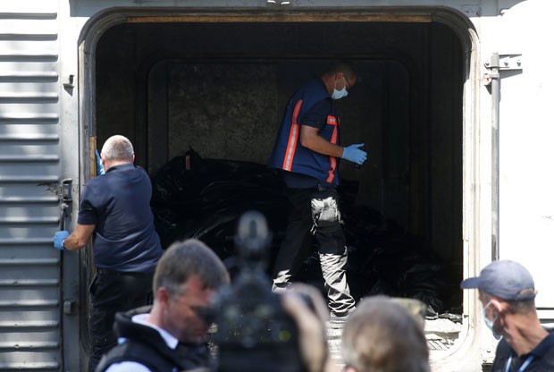 Monitores da OSCE e investigadores holandeses inspecionam os corpos das vítimas do voo MH17 nesta segunda-feira (21) no leste da Ucrânia. Corpos foram colocados em trem refrigerado (Foto: Maxim Zmeyev/Reuters)