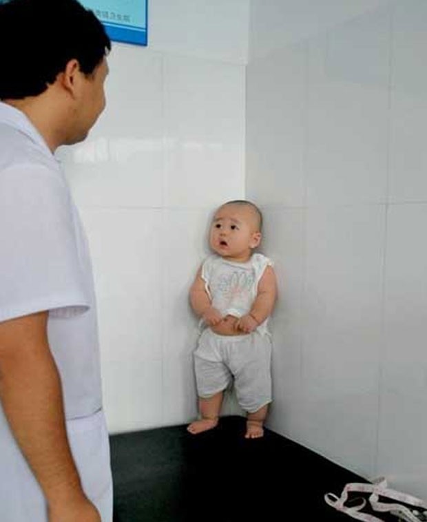 Bebê chinês se escondeu em um canto com aparente medo de tomar uma injeção. (Foto: Reprodução)