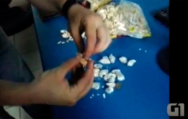 Um a um os pacotes de droga foram colocados entre as camadas das bolachas (Foto: Reprodução/Vídeo cedido ao G1 pela Coape)