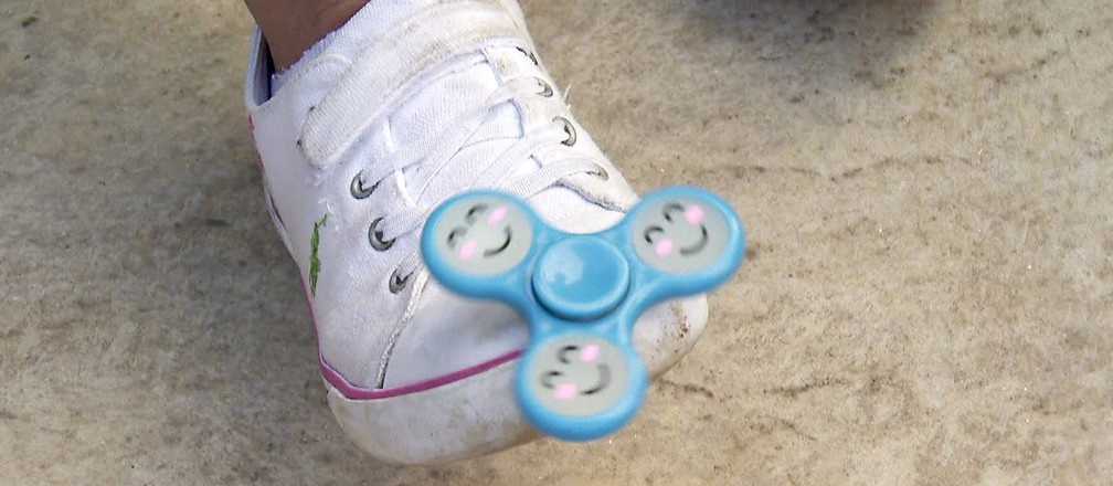 Criança brinca com spinner em seus pés (Foto: Reprodução/Globo)