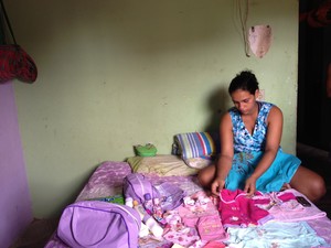 Raquel olha as roupinhas da filha que não pode levar para casa (Foto: Tarsira Rodrigues/G1)