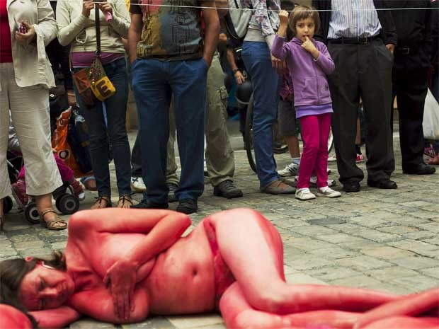 Garota olha para grupo que faz protesto contra a tourada nesta quinta (5) na Espanha. Os manifestantes se pintaram de vermelho e preto e formaram a frase ‘parem com a tourada’. No dia 6, o festival de tourada San Fermin começa em Pamplona, durando uma sem (Foto: Reuters)