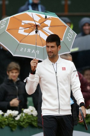 Novak Djokovic com guarda-chuva no jogo contra Roberto Bautista Agut em Roland Garros (Foto: Reuters)