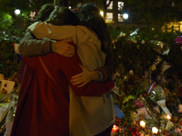 Pessoas se abraçam em frente a um memorial perto da casa de shows Bataclan, durante homenagem aos mortos nos ataques terroristas de Paris, na sexta (20) (Foto: AFP Photo/Bertrand Guay)