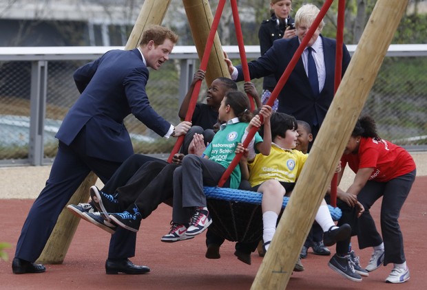 Principe Harry brincando de balanço com as crianças (Foto: Reuters/Agência)