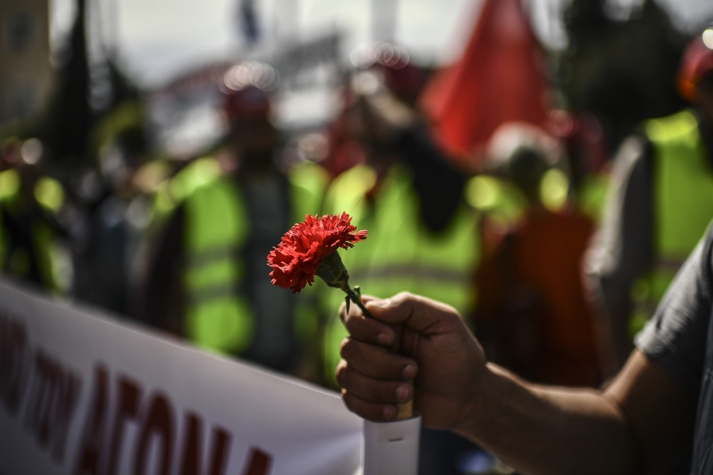 Integrante da União Trabalhista Grega (PAME) segura um cravo durante uma manifestação pelo 1º de maio, nesta quarta. — Foto: Aris Messinis / EUA / AFP