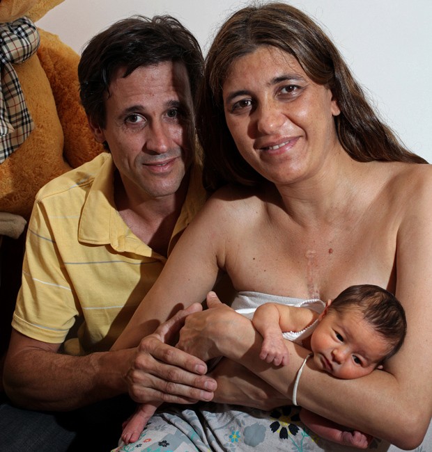 A paciente transplantada Juliana Finondo, de 39 anos, segura sua filha Emília junto com o marido, Gerardo Tuya, em Buenos Aires (Foto: Marcelo Gomez/AFP)