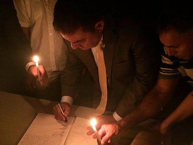 Prefeito de Curral de Cima precisou da ajuda de correligionários para assinar a posse à luz de velas (Foto: Totó Ribeiro/Arquivo Pessoal )