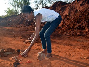 Marlene separa possíveis ossos e roupas tiradas de cemitério em Ribeirão Preto (Foto: Clayton Castelani/ G1)