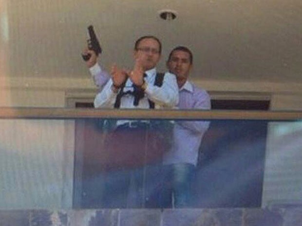 Mensageiro do hotel algemado na varanda de um dos quartos com o sequestrador armado atrás  (Foto: Polícia Civil/Divulgação)