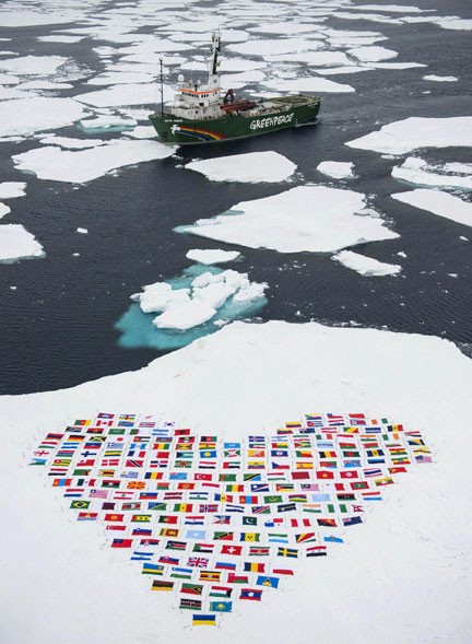 Bandeiras dos 193 países que integram a ONU são vistas na neve em frente ao navio My Arctic Sunrise, do Greenpeace, em foto do dia 14 divulgada nesta quarta (19). A organização aproveitou a viagem para apelar à ONU por medidas contra o degelo do Ártico. (Foto: AFP/Danile Beltra/Greenpeace)