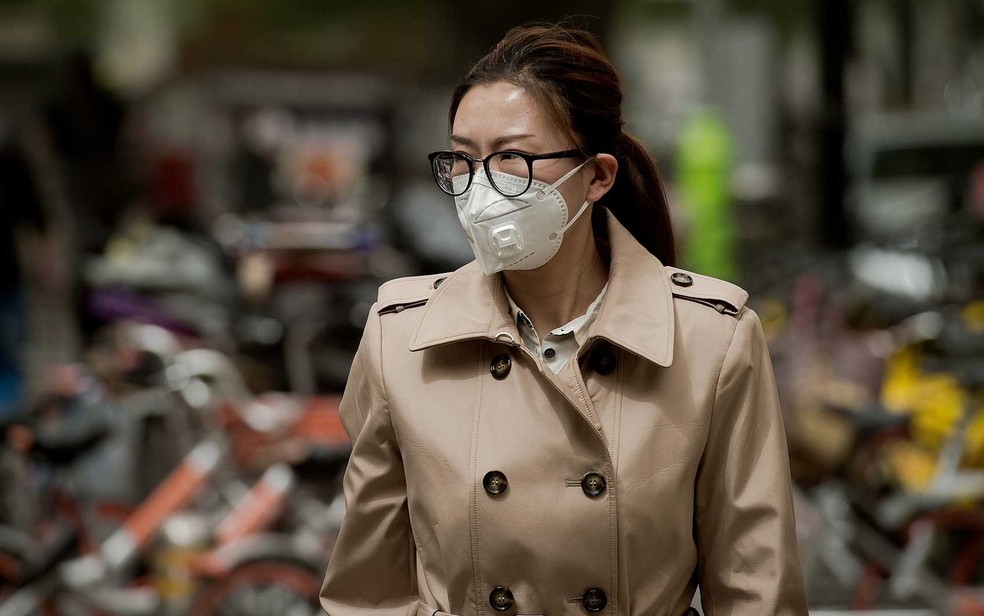 Mulher usa uma máscara contra poluição por partículas de areia em Pequim (Foto: Nicolas Asfouri / AFP Photo)