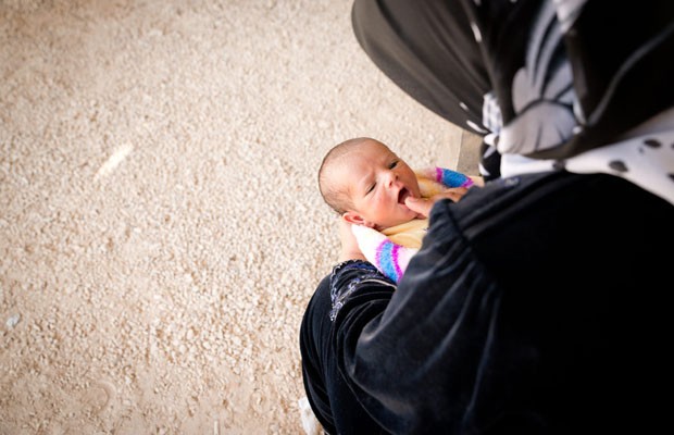 Mãe aguarda com bebê fora da tenda para ser registrado em campo na Jordânia (Foto: J. Kohler/Unhcr)
