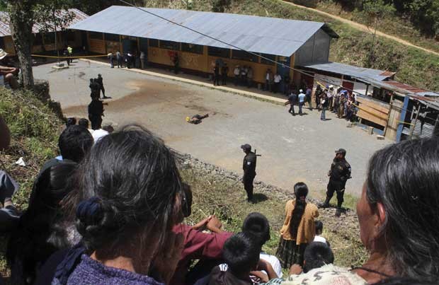 Grupo de pessoas observa corpo linchado de homem acusado de matar duas crianças na Guatemala (Foto: Reuters)