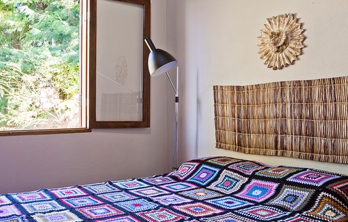 Na casa do arquiteto Ricardo Caminada, em Gonçalves, Minas Gerais, o quarto de casal tem uma esteira de palha, que foi utilizada como cabeceira. Sobre a cama, colcha de crochê de lã