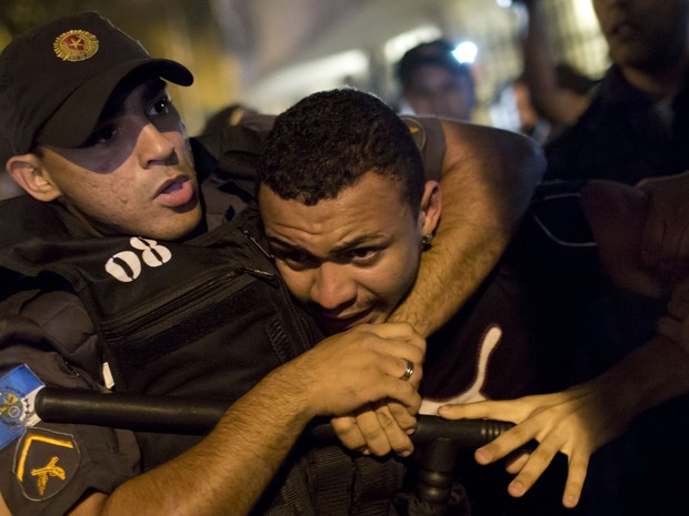 Policial detém manifestante em protesto no Rio de Janeiro nesta segunda-feira (12). (Foto: Felipe Dana/AP)