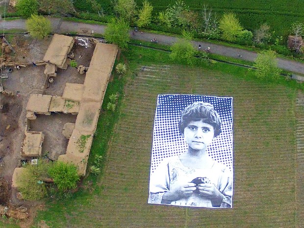Foto gigante de menina paquistanesa que perdeu os pais num ataque aéreo por drone, é exposta em região tribal de Khyber-Pakhtunkhwa, que abriga militantes da Al-Qaeda. O projeto &#39;Inside Out&#39; visa conseguir &#39;empatia&#39; dos controladores de drones americanos (Foto: AFP/Inside Out Project)